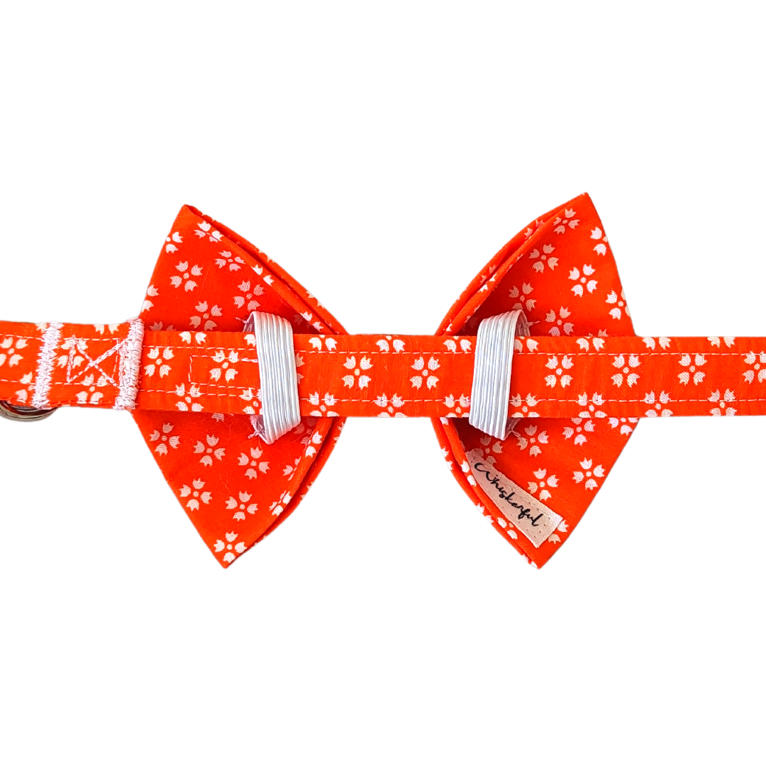 Image of the back of our Bright Orange with White Floral Bow Tie, showcasing two elastic loops on each side for easy attachment to the collar. The elastics ensure a secure and droop-free fit.