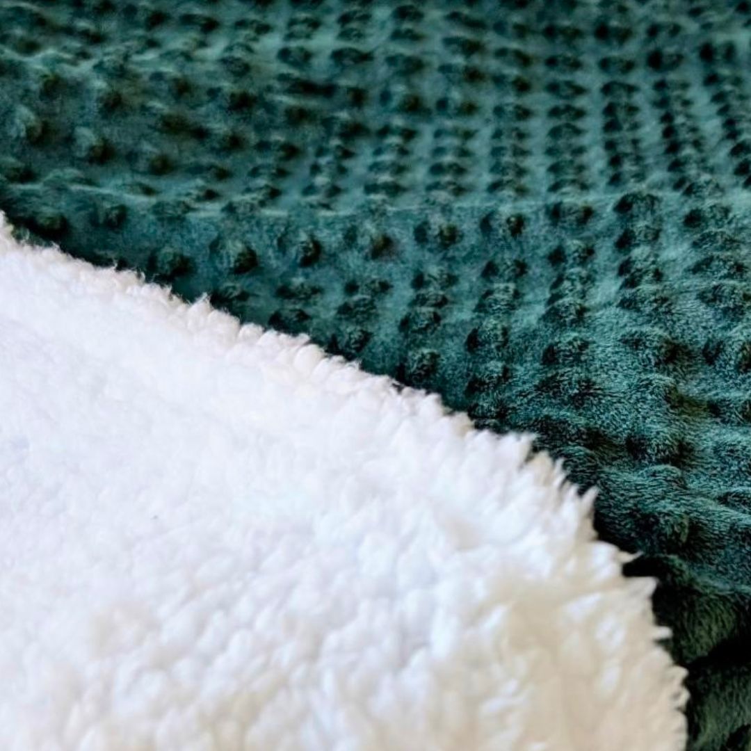 Close-up of emerald green fabric and white faux sherpa fabric sleeping bag