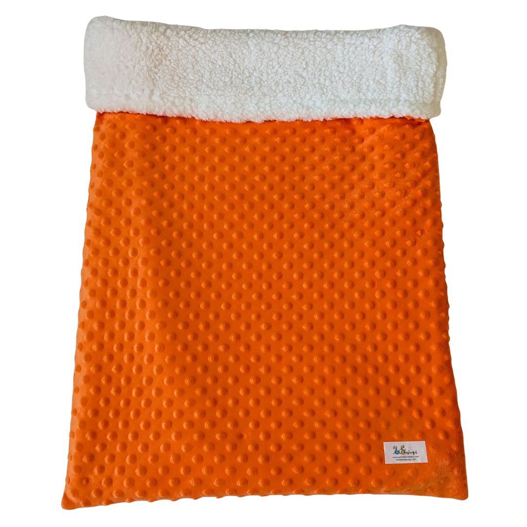 Vibrant orange faux Sherpa pet bed rolled up for travel or lounging.