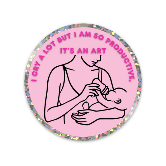Pink round sticker with illustration of a person holding a baby, bottle feeding and text "I Cry A lot But I Am So Productive, It's an Art"
