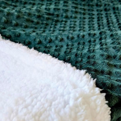 Close-up of emerald green fabric and white faux sherpa fabric sleeping bag